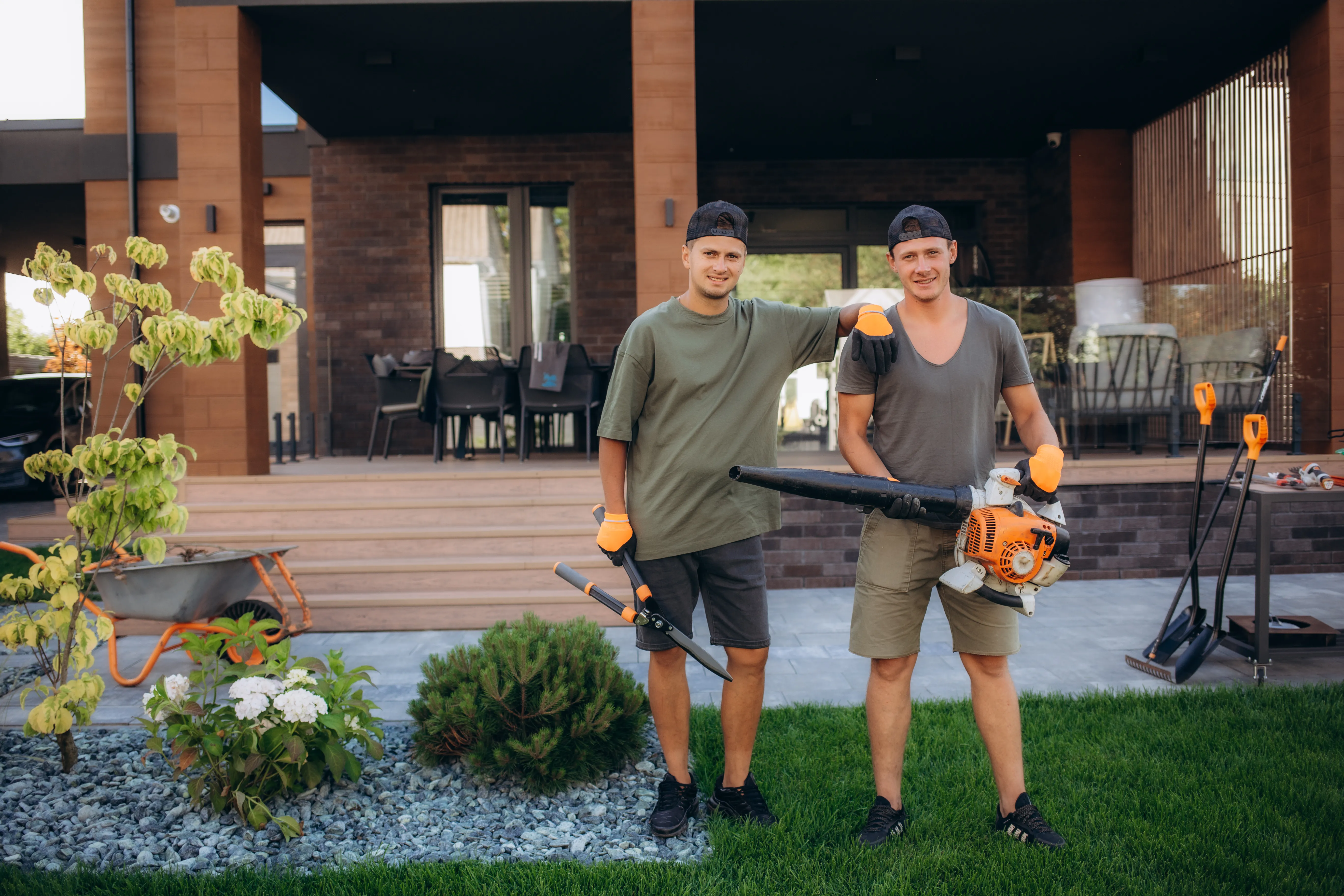Two lawn crew members with a blower and a trimmer